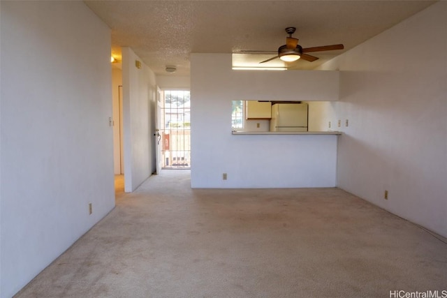 unfurnished living room featuring light carpet, a textured ceiling, and ceiling fan