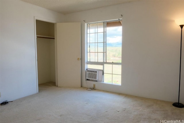 unfurnished bedroom featuring a wall mounted AC, light carpet, and a closet