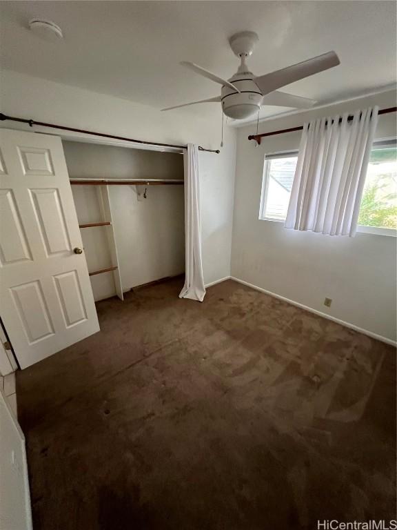 unfurnished bedroom featuring ceiling fan, a closet, and dark colored carpet