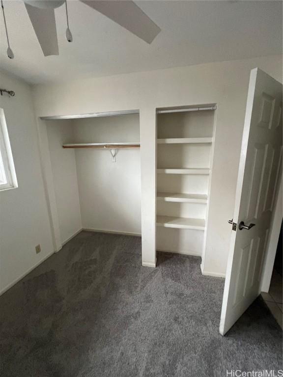 unfurnished bedroom with ceiling fan, multiple closets, and dark colored carpet