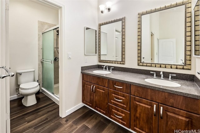 bathroom featuring toilet, vanity, a shower with shower door, and hardwood / wood-style flooring