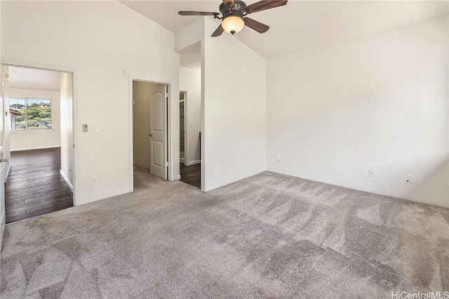 empty room with ceiling fan, vaulted ceiling, and dark colored carpet