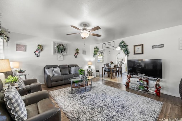 living room featuring ceiling fan and dark wood-type flooring