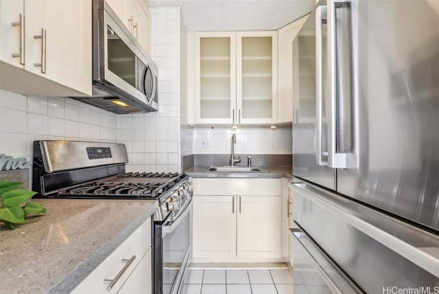 kitchen featuring backsplash, light tile patterned floors, sink, and appliances with stainless steel finishes