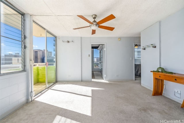 carpeted empty room featuring ceiling fan and a textured ceiling