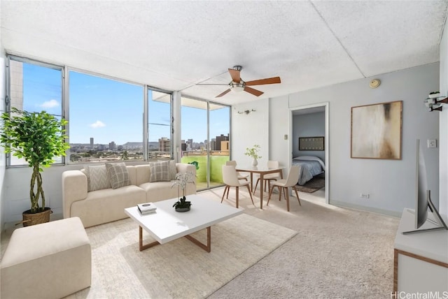 living room featuring a textured ceiling, ceiling fan, expansive windows, and light carpet