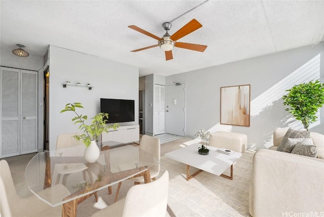 living room featuring ceiling fan and a textured ceiling