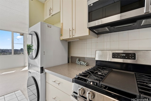 kitchen featuring backsplash, stacked washing maching and dryer, stainless steel appliances, and light carpet