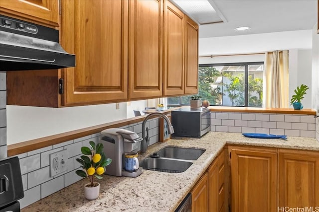 kitchen with decorative backsplash, light stone counters, and sink