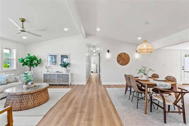 dining space with ceiling fan, light hardwood / wood-style flooring, and vaulted ceiling with beams