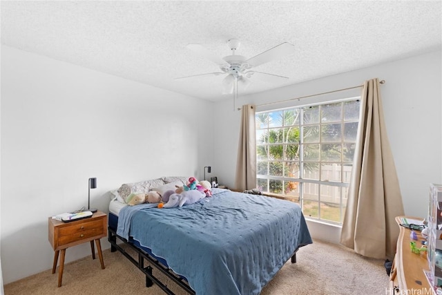 bedroom with ceiling fan, light carpet, and a textured ceiling