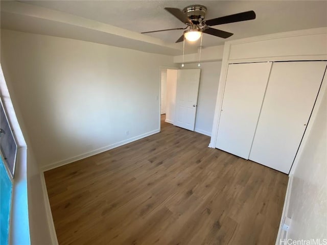 unfurnished bedroom with a closet, ceiling fan, and dark wood-type flooring