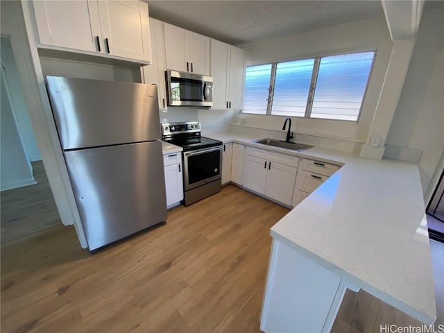 kitchen featuring white cabinets, sink, light hardwood / wood-style flooring, appliances with stainless steel finishes, and light stone counters