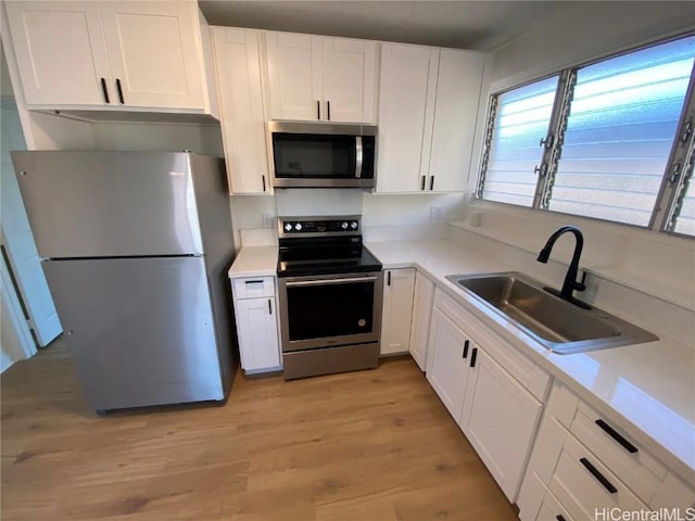 kitchen featuring white cabinets, appliances with stainless steel finishes, light wood-type flooring, and sink