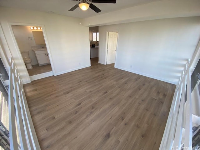 unfurnished bedroom featuring ceiling fan, ensuite bathroom, and dark hardwood / wood-style floors