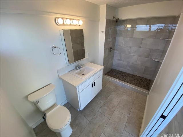 bathroom with toilet, vanity, and tiled shower