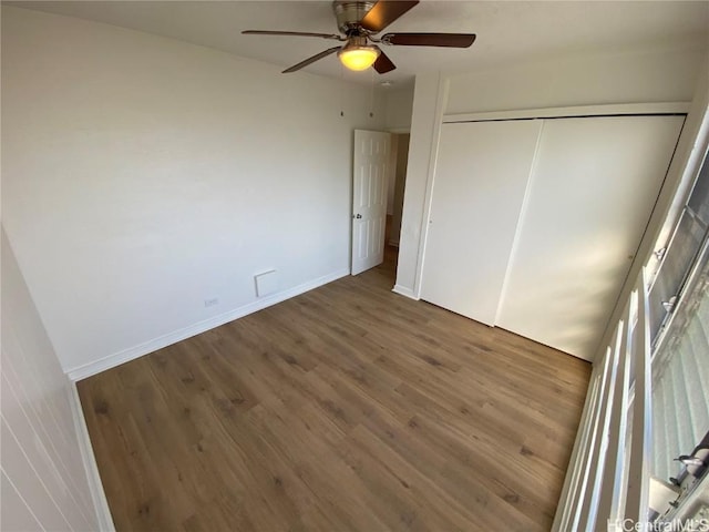 unfurnished bedroom featuring hardwood / wood-style floors, a closet, and ceiling fan