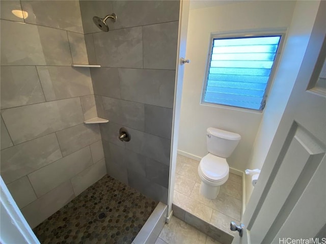 bathroom featuring tile patterned floors, toilet, and tiled shower