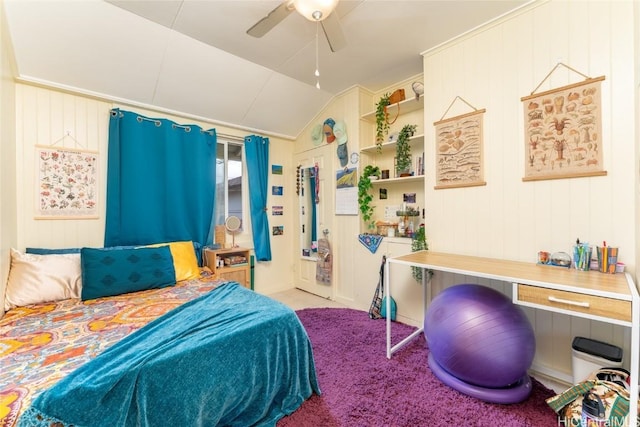 carpeted bedroom with ceiling fan, wooden walls, and vaulted ceiling