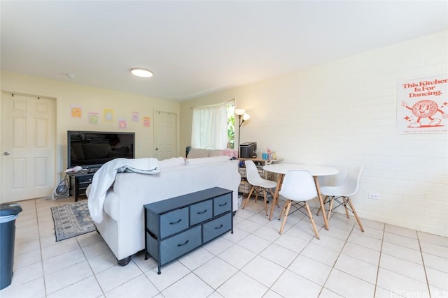 bedroom with light tile patterned floors and brick wall