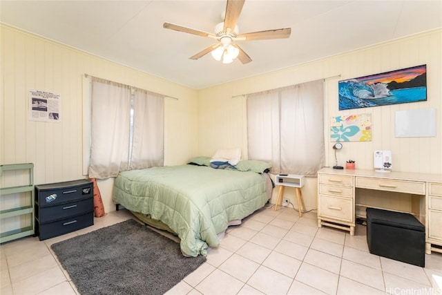 bedroom featuring ceiling fan, wooden walls, and light tile patterned flooring