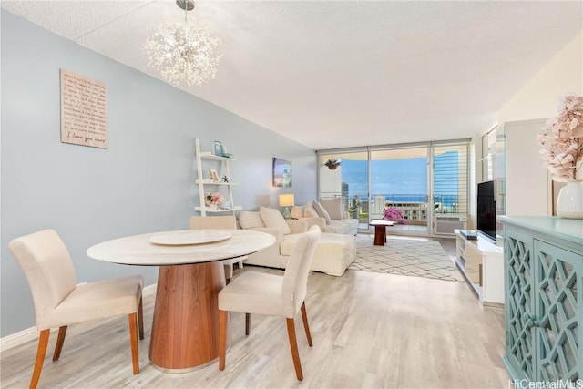 dining space featuring expansive windows, light hardwood / wood-style floors, a textured ceiling, and an inviting chandelier