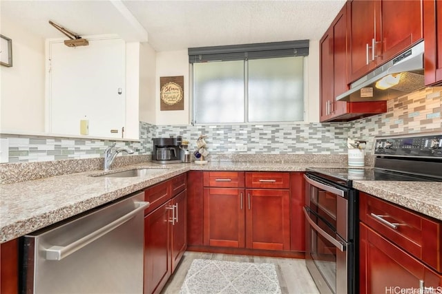 kitchen with appliances with stainless steel finishes, backsplash, light stone counters, and sink