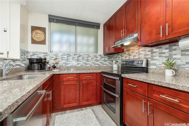 kitchen featuring decorative backsplash, light wood-type flooring, a textured ceiling, stainless steel appliances, and sink