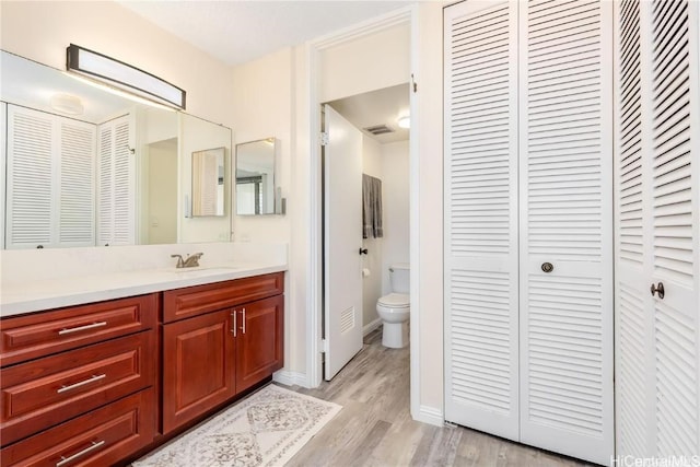 bathroom featuring toilet, vanity, and hardwood / wood-style flooring