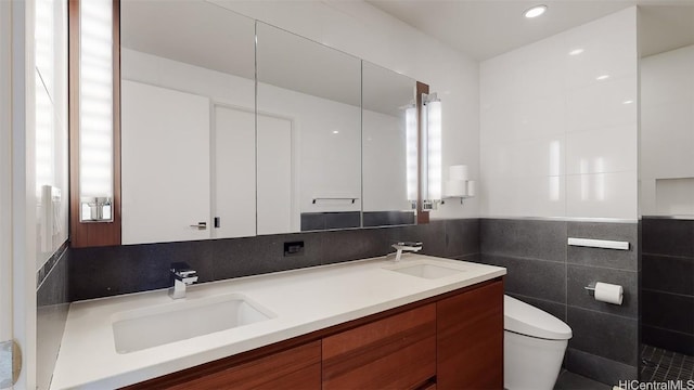 bathroom featuring vanity, toilet, and tile walls