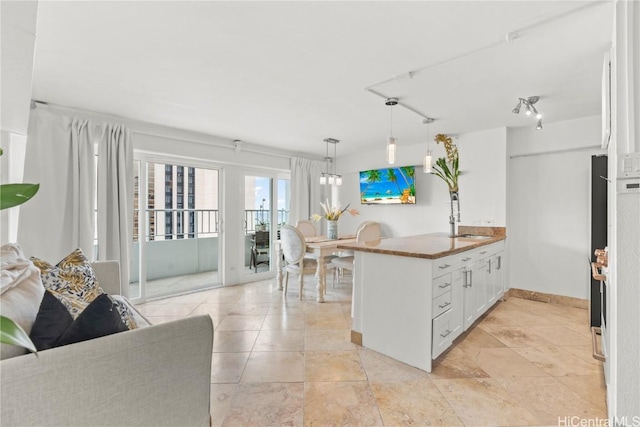 kitchen featuring kitchen peninsula, white cabinetry, hanging light fixtures, and sink