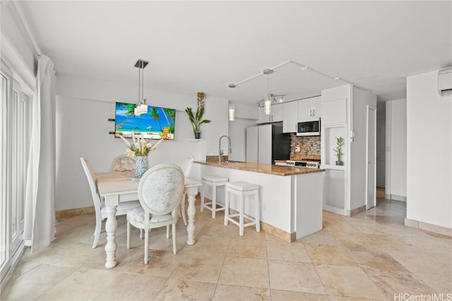 kitchen with white cabinetry, tasteful backsplash, kitchen peninsula, refrigerator, and decorative light fixtures