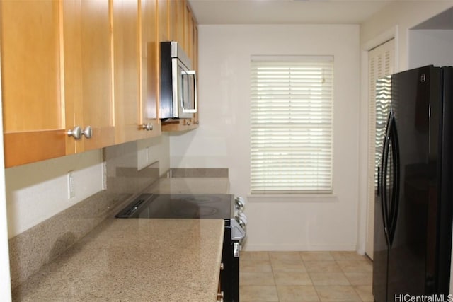 kitchen with light stone counters, light tile patterned floors, and stainless steel appliances