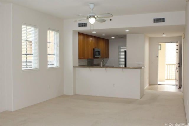 kitchen featuring kitchen peninsula, ceiling fan, sink, and light colored carpet