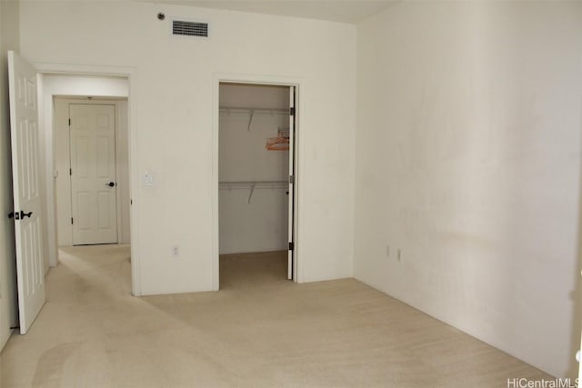 unfurnished bedroom with a spacious closet, a closet, and light colored carpet