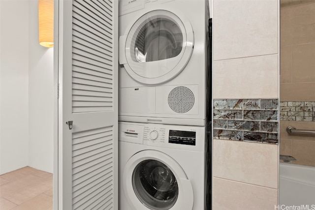 laundry room featuring light tile patterned flooring and stacked washer / drying machine