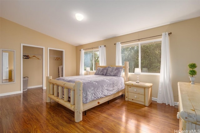 bedroom with a walk in closet, lofted ceiling, and hardwood / wood-style flooring