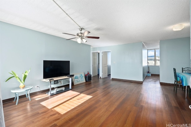 living room with a textured ceiling, ceiling fan, and dark hardwood / wood-style floors