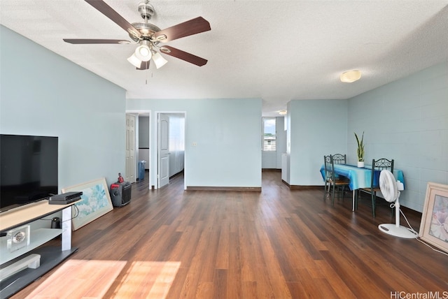 living room featuring ceiling fan, dark hardwood / wood-style floors, and a textured ceiling