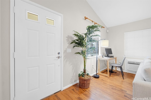 foyer featuring a wall mounted air conditioner, wood-type flooring, and vaulted ceiling