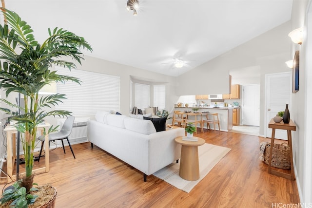 living room featuring ceiling fan, lofted ceiling, and light wood-type flooring