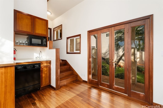 kitchen featuring sink, light hardwood / wood-style floors, lofted ceiling, and black appliances