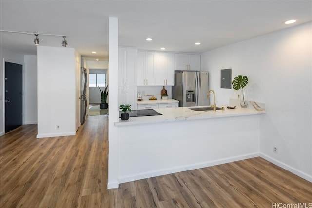 kitchen featuring wood-type flooring, stainless steel fridge, white cabinets, and sink