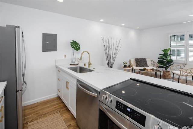 kitchen featuring light wood-type flooring, stainless steel appliances, sink, electric panel, and white cabinetry