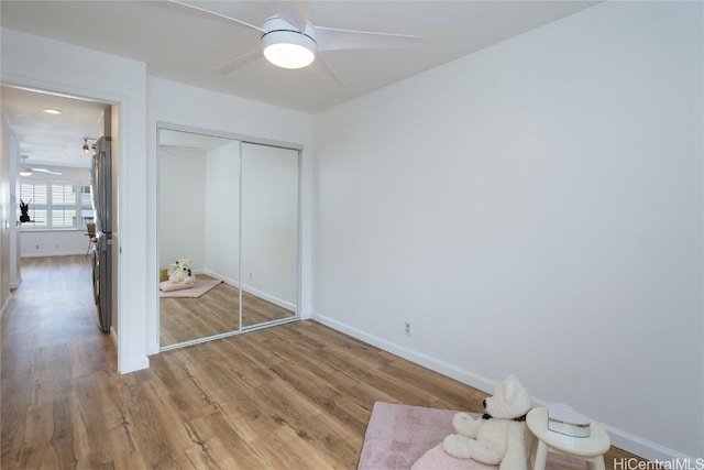 unfurnished bedroom with stainless steel refrigerator, ceiling fan, a closet, and light hardwood / wood-style flooring