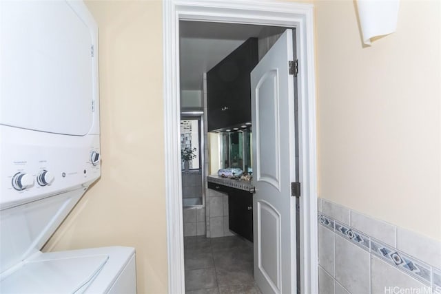 clothes washing area featuring stacked washing maching and dryer and tile patterned floors