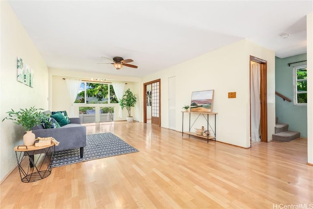 living room featuring light wood-type flooring, ceiling fan, and a healthy amount of sunlight