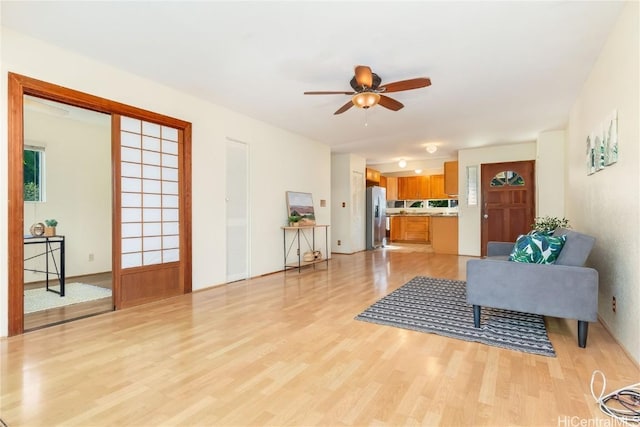 living room with ceiling fan and light hardwood / wood-style flooring