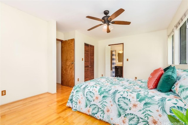 bedroom with ceiling fan, ensuite bathroom, wood-type flooring, and two closets