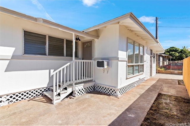 doorway to property with fence and a wall mounted AC